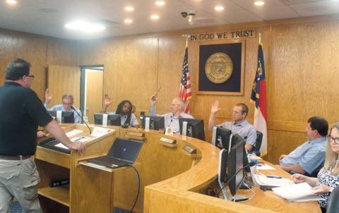 Press photo/Thomas Sherrill - Commissioners Gary Shields, Danny Antoine, Paul Higdon and Josh Young vote for solid waste fee hikes during a special called meeting on Monday, June 26. Commissioner John Shearl, sitting next to Young, voted against the fee increases. Also pictured is Solid Waste Director Chris Stahl (far left) and County Finance Director Lori Carpenter (far right).