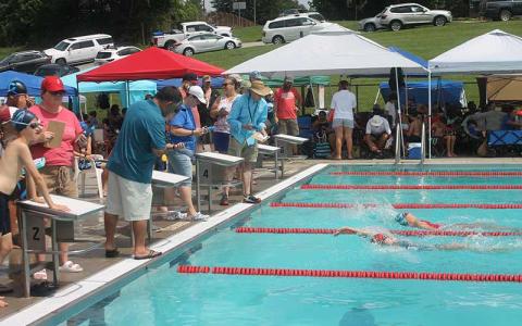 Press photo/Will Woolever - Timers watch a close finish between FAST Fins Rylee Rogers (foreground) and Bri Dezarn in the girls 11-12 50-yard backstroke July 15 at the Macon County Rec Park.