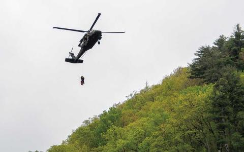 Photo/Bob Scott - A National Guard helicopter was called in to help rescue a man who had fallen down the California Mountain side of the Cullasaja Gorge. After lifting the man from the side of the mountain, the helicopter then returned to lift the rescue workers who had repelled down the mountain.