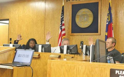 Press photo/Thomas Sherrill - Commissioners Danny Antoine, Gary Shields and Josh Young vote in favor of the $63.7 million budget for the 2024-25 fiscal year at the June 11 Macon County Board of Commissioners meeting.