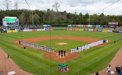 Photo/Tennessee Smokies - The Tennessee Smokies (right) and the Rocket City Trash Pandas (left) stand on the field for the national anthem on opening day, April 5, at Smokies Stadium in Kodak, Tennessee.