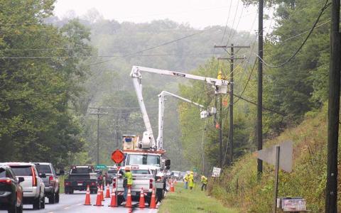 Press photo/Thomas Sherrill - Crews work midday Friday on restoring power lines hit by a falling tree on Highlands Road near River Bottom Lane in the Cullasaja community. Winds arrived after Thursday and Friday morning’s rainfall and caused many saturated trees and power lines to fall.