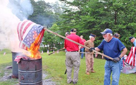 Press photo/Vickie Carpenter - Will Williams places a flag in one of the burn barrels during the American Legion’s flag retirement ceremony.