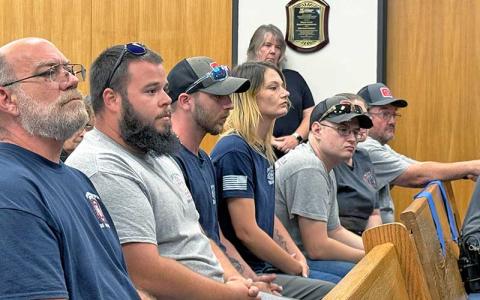 Press photo/Mia Overton - Members of the Burningtown-Iotla Fire Department listen during a report at the July 8 Macon County Board of Commissioners meeting.