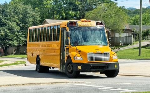 Press photo/Mia Overton. A Macon County school bus as it navigates the roundabout at Wayah and Depot streets. A shortage of bus drivers has left some parents struggling to get their children to school on time and having to leave work early for afternoon pickups.