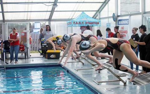 Press photo/Will Woolever - Macon Early College and Franklin High School swimmers dive off their starting blocks side-by side in the girls 500-yard freestyle at Franklin Health and Fitness Nov. 22. From right are Dalila Canzone (FHS), Alyse Remery (MEC) and Eleanor Kessler (MEC).