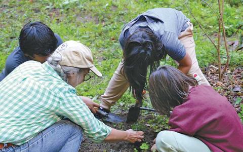Photo submitted - Noquisi Initiative Executive Director Elaine Eisenbraun plants perennial shrubs and ground cover for the Cherokee Food Forest with K-6 students from New Kituwah Academy. 