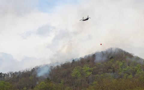Press photo/Shelby Powell. A helicopter crew brings in more water to support ground operations in fighting a forest fire in the Needmore area on Friday, April 3. 
