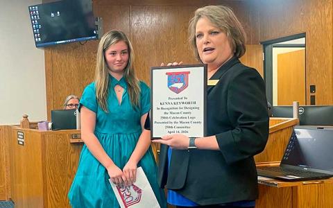 Press photo/Shelby Powell - Kenna Keyworth (left), winner of the Macon 250th Celebration Committee's logo contest, stands with committee spokesperson Amie Owens, displaying Keyworth's submission. 
