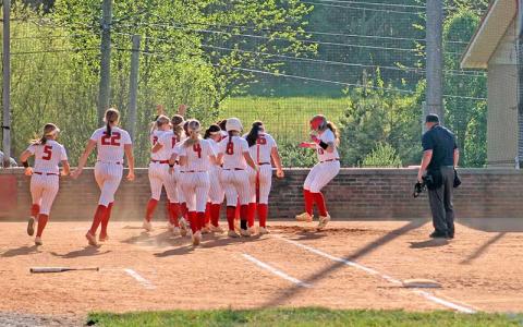 Meliah Mason (right) is mobbed by teammates at home plate after one of her two home runs versus North Henderson April 16. (Press photo/Will Woolever)