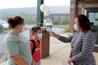 Press photo/Jake Browning - Students and their parents all need to get their temperature checked before entering a school building. From left: Danielle Bryson, sixth-grader Jet Carroll and Mountain View Intermediate School principal Nancy Breedlove