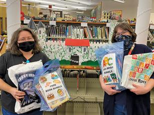Press photo/Jake Browning - Angie Walker and Tabitha Johnson show off some of the book bundles and take-home activity bags that are now available to patrons of the Macon County Public Library’s children’s department. 
