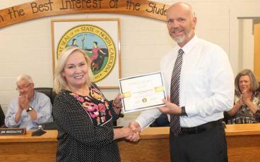 Macon Early College guidance counselor Kathy Breedlove (left) accepts an award from Macon County School superintendent Chris Baldwin for MEC’s 100% graduation rate.