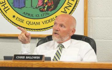 Press photo/Thomas Sherrill - Dr. Chris Baldwin points to the screen to make a point during a discussion at the June 26 meeting of the Macon County Board of Education. The June meeting was the last for the retiring superintendent. 