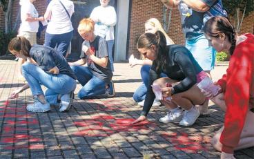 Press photo/Thomas Sherrill - Members of the Franklin High School Interact Club participate in the Red Sand Project on Sept. 30. The red sand represents how the victims of human trafficking fall through the cracks but are still visible.