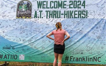 Photo courtesy of Bob Scott - A hiker checks out the signatures of her fellow Appalachian Trail hikers on the welcome board on Main Street, Franklin.