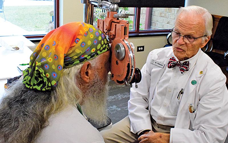 Press photo/Linda Mathias - Dr. LeRoy Roberson performs an eye exam for a veteran during Thursday’s Stand Down. 