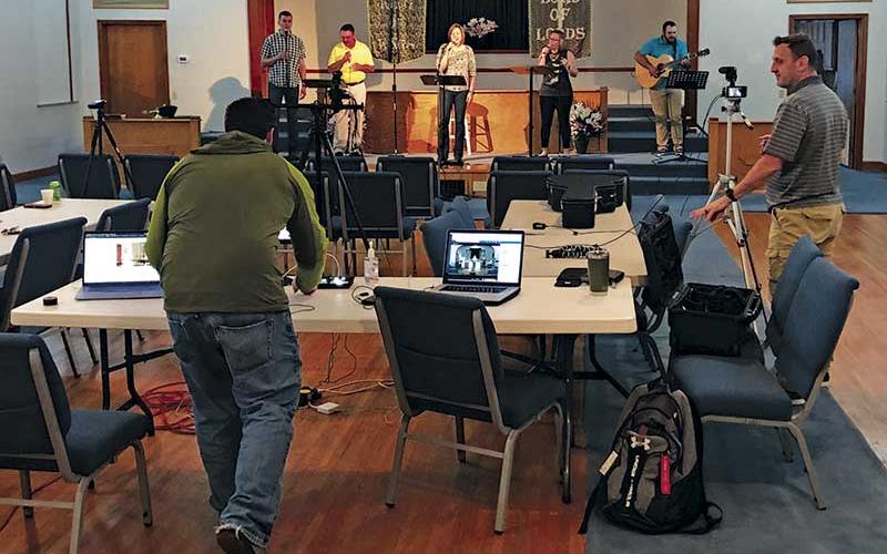 Photo submitted - Daniel Rogers, left, and Lee Cloer work the computers during a live-streamed  service at Holly Springs Baptist Church. On stage, from left, are Matt Corbin, Kelly Corbin, Kathi Graham and Katie LaFlamm.