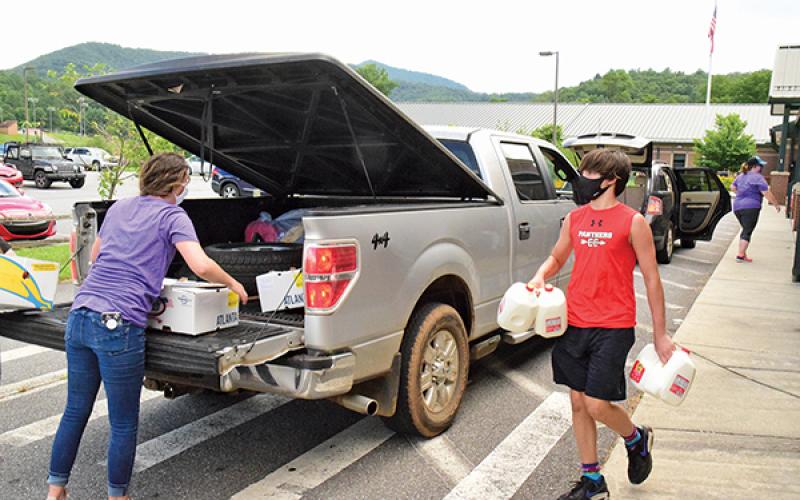 Press photo/Linda Mathias - Volunteers bring food to vehicles lined up at Mountain View Intermediate School on Monday, July 27.