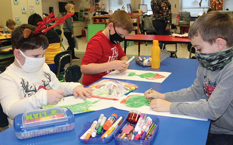 Press photo/Jake Browning - Students in Crystal Teem’s first-grade class at South Macon Elementary School wear their masks while they work on a Grinch-themed coloring project. From left: Liam Long, Austin Trivett and Rylan Armstrong.
