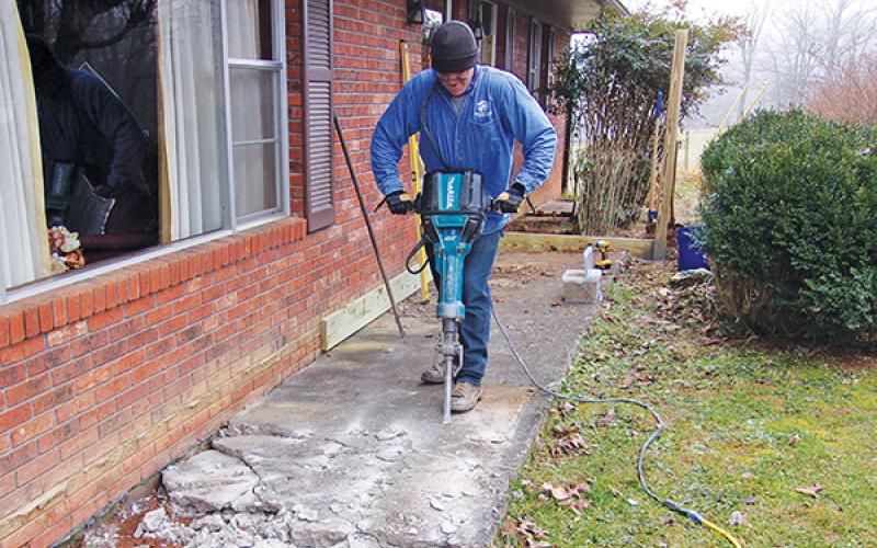 Submitted photo/Habitat - John Wert of Habitat for Humanity removes a sidewalk at Vaughn Sanders’ home as part of the Healthy Home Initiative. The sidewalk was sunken and too narrow for Sanders’ wheelchair, so the construction crew replaced it with a front porch and ramp.