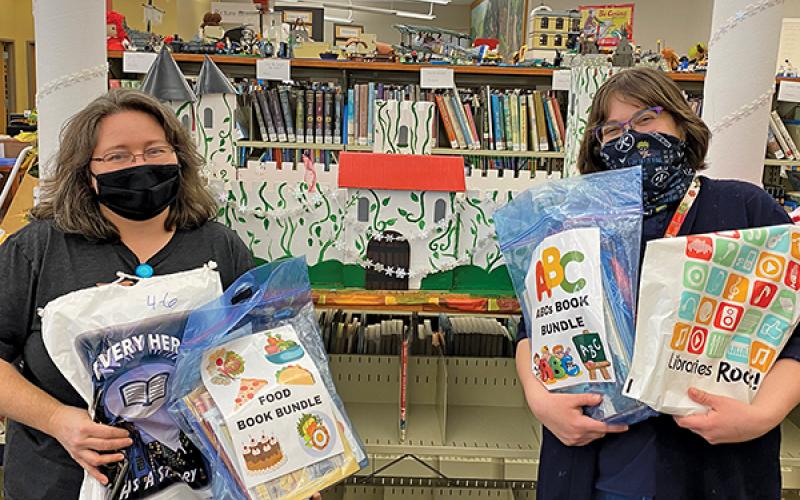 Press photo/Jake Browning - Angie Walker and Tabitha Johnson show off some of the book bundles and take-home activity bags that are now available to patrons of the Macon County Public Library’s children’s department. 