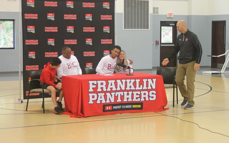 Press Photo/Will Woolever FHS point guard chad Wilson hugs his mom, Stephanie Moore, after signing his official offer to Bryan College while Braeden and William Moore look on.