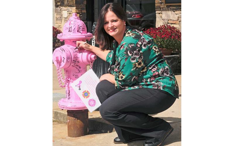 Press photo/Braulio Fonseca - Breast cancer survivor Gwen Stanfield signs the pink fire hydrant on Main Street.